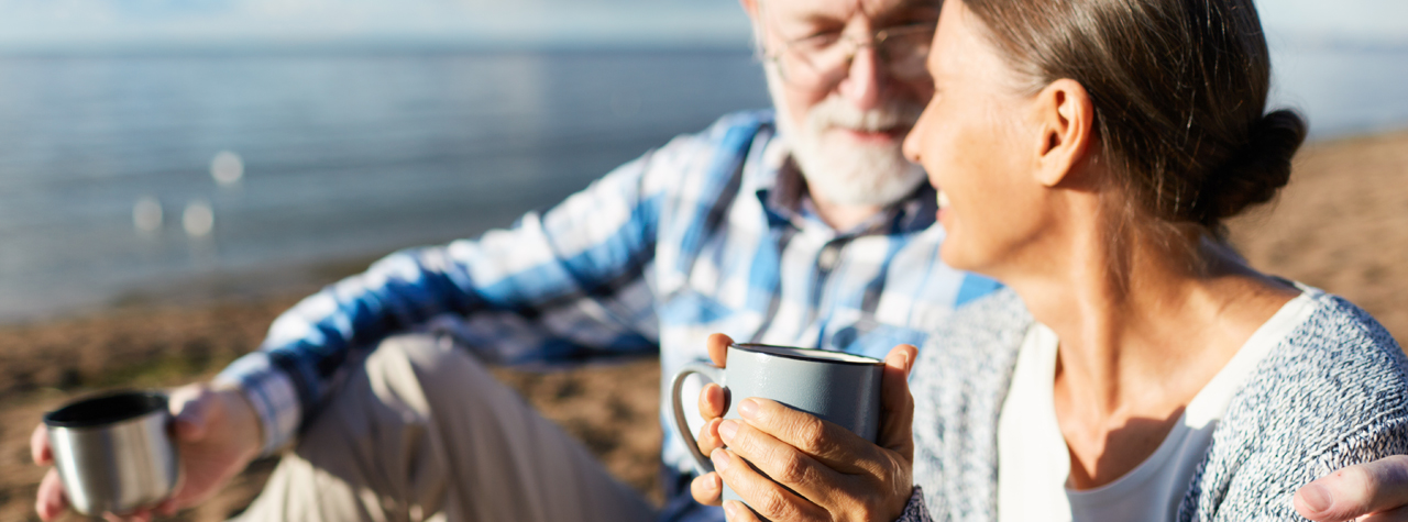 older Man and woman drinking coffe by the beach