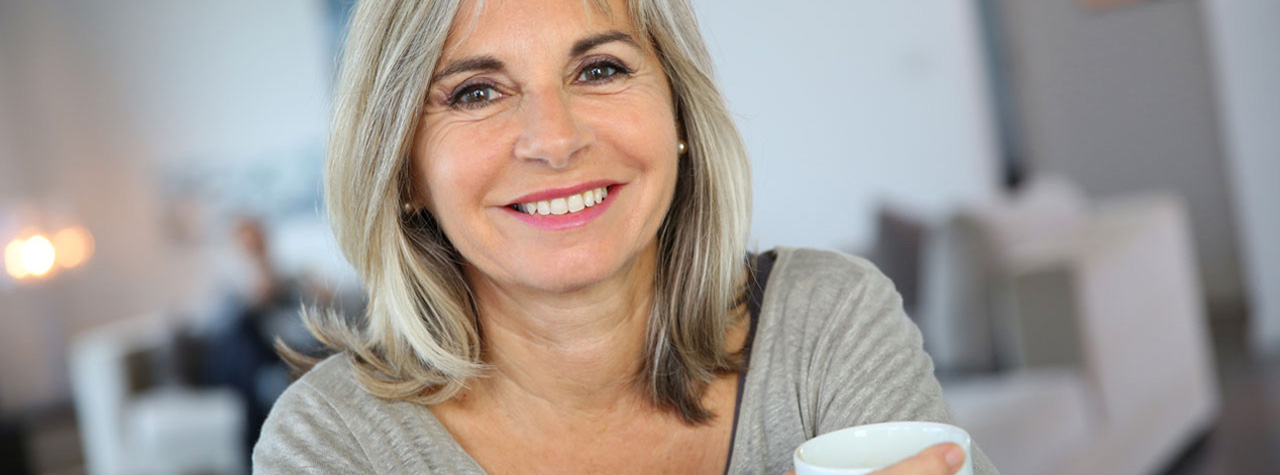 older woman holding a cup smiling