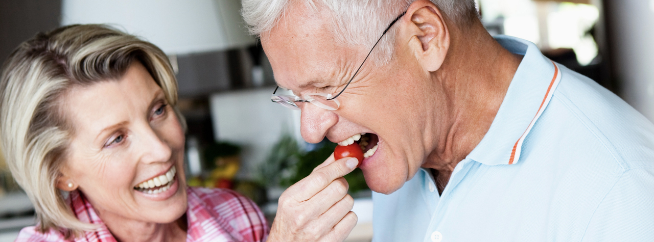 older woman feeding sallad to a man